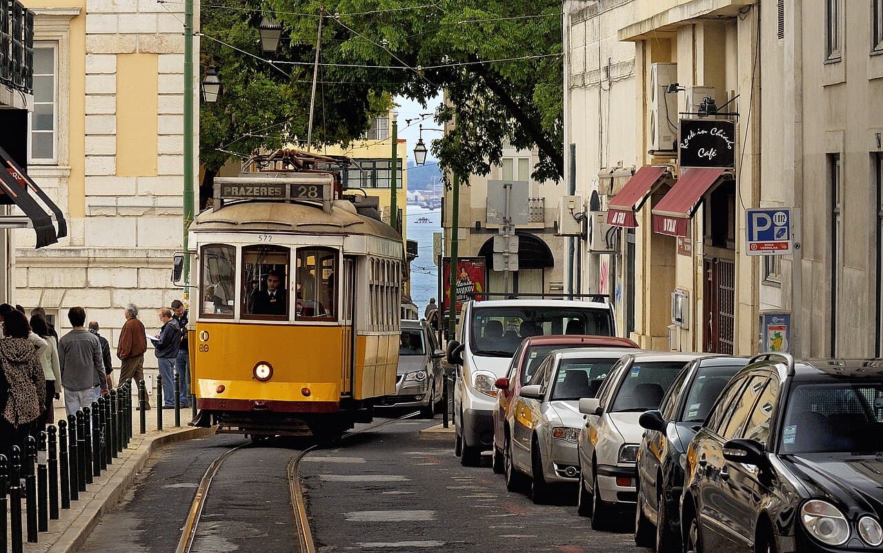 A yellow vintage tram climbing a narrow Lisbon street