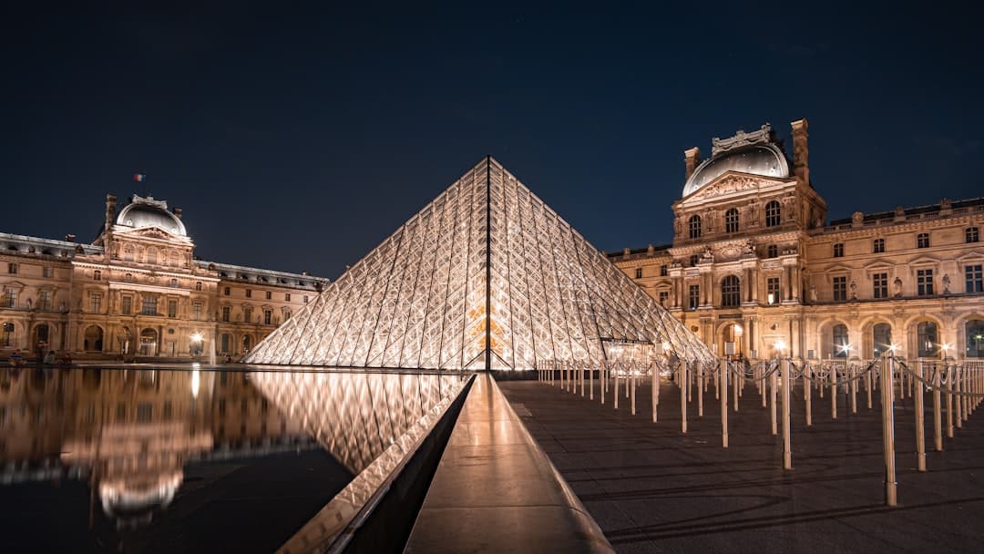 The glass pyramid of the Louvre with the palace wings at dusk